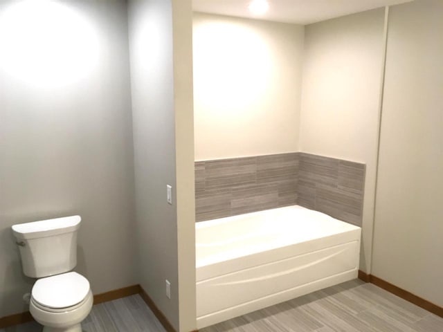 bathroom with a tub to relax in and toilet