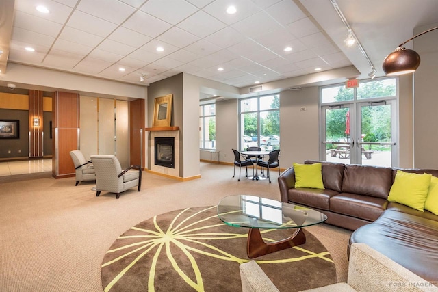 living room featuring a tile fireplace, a paneled ceiling, rail lighting, light carpet, and french doors