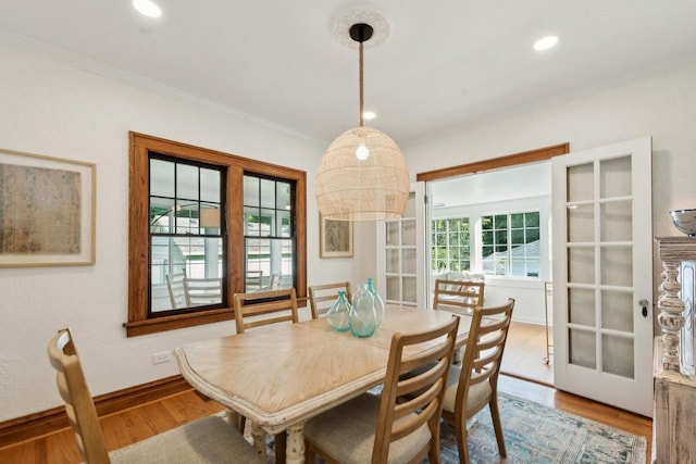 dining area with crown molding, light wood-type flooring, and french doors