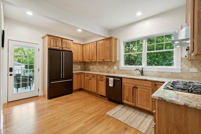 kitchen with sink, light hardwood / wood-style flooring, extractor fan, black appliances, and light stone countertops