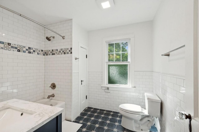 full bathroom with tile patterned floors, toilet, tile walls, vanity, and tiled shower / bath combo