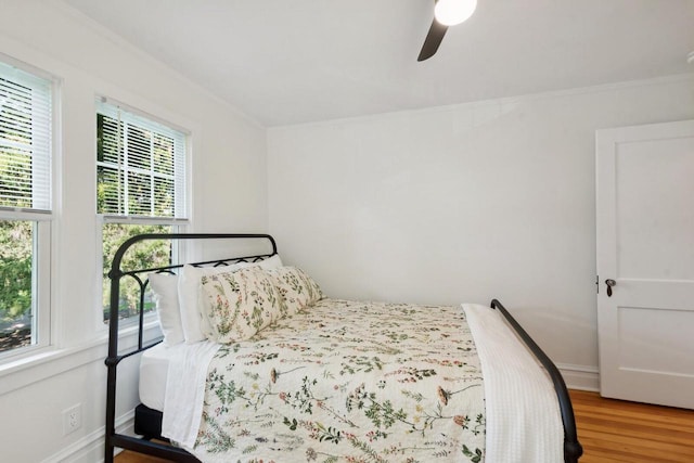 bedroom with hardwood / wood-style flooring, ornamental molding, and ceiling fan