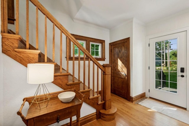 entryway with crown molding, a wealth of natural light, and light wood-type flooring