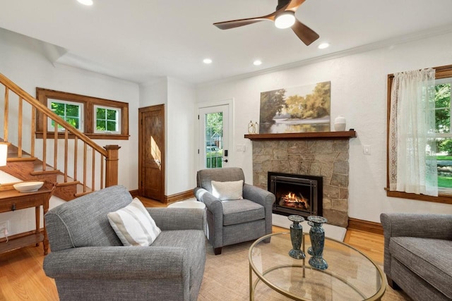 living room with a stone fireplace, light hardwood / wood-style flooring, and a wealth of natural light