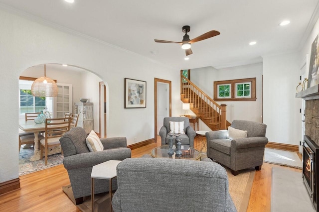 living room with ornamental molding, a wealth of natural light, a fireplace, and light hardwood / wood-style floors