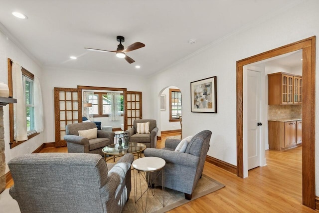 living room with ornamental molding, ceiling fan, and light hardwood / wood-style flooring