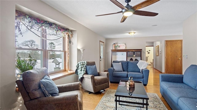 living room featuring a textured ceiling, light hardwood / wood-style flooring, and ceiling fan