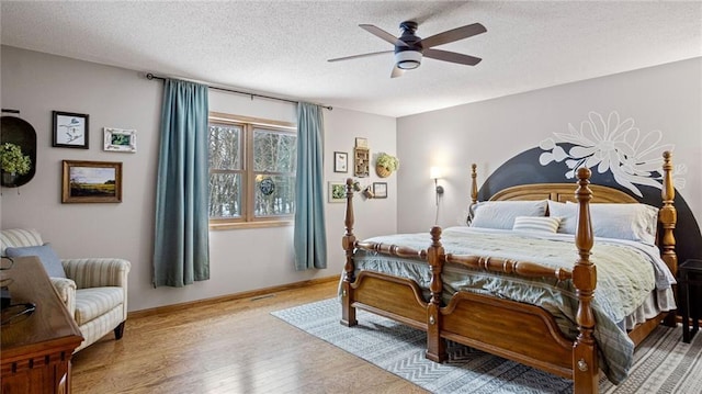 bedroom with ceiling fan, hardwood / wood-style flooring, and a textured ceiling