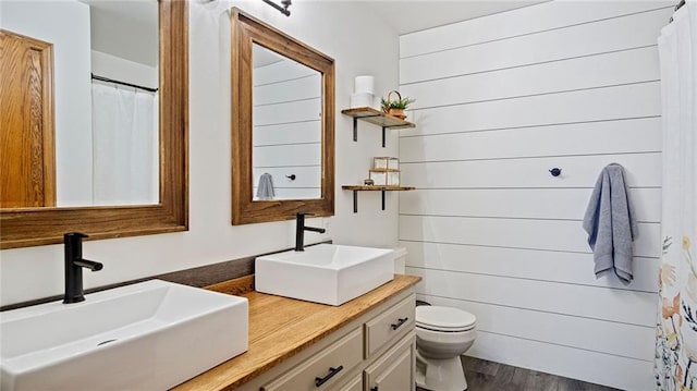 bathroom with vanity, hardwood / wood-style floors, wooden walls, and toilet