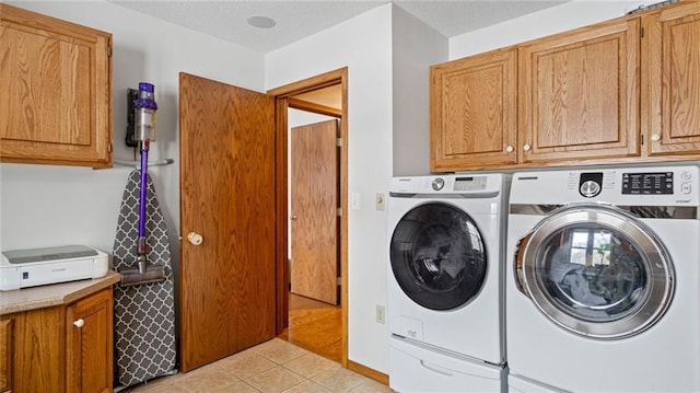 clothes washing area featuring cabinets, washing machine and dryer, and light tile patterned floors