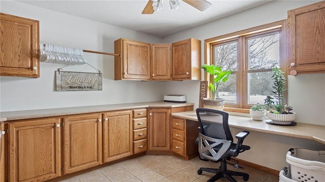 tiled office space featuring ceiling fan, built in desk, and a textured ceiling