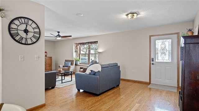 living room featuring ceiling fan, a textured ceiling, and light wood-type flooring