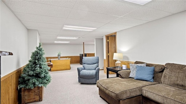 carpeted living room featuring a drop ceiling and wooden walls