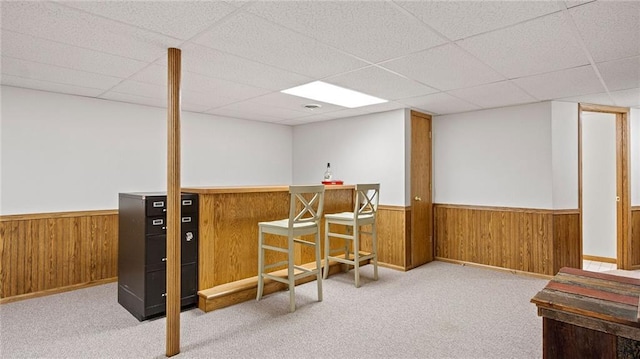 bar featuring a drop ceiling, light colored carpet, and wood walls