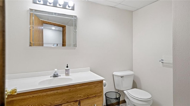 bathroom with vanity, toilet, and a drop ceiling