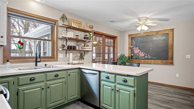 kitchen featuring sink, stainless steel dishwasher, kitchen peninsula, and green cabinetry