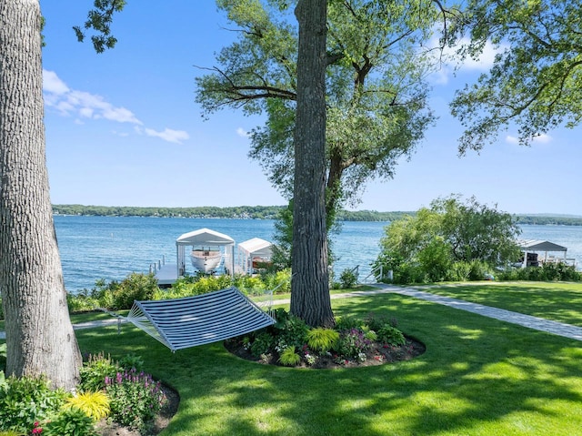 surrounding community with a water view and a lawn