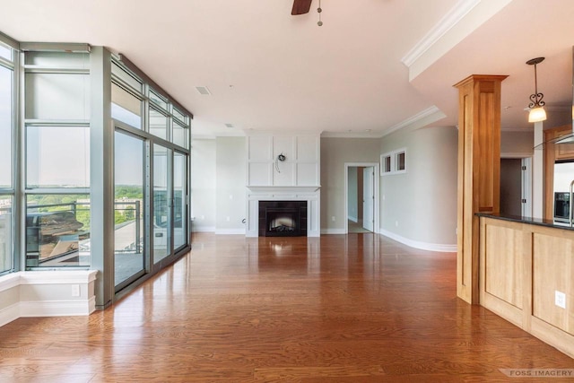 unfurnished living room with dark hardwood / wood-style flooring, a tiled fireplace, ornamental molding, ceiling fan, and floor to ceiling windows