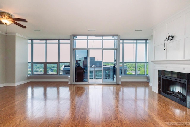 unfurnished living room with hardwood / wood-style flooring, ceiling fan, ornamental molding, and a tiled fireplace