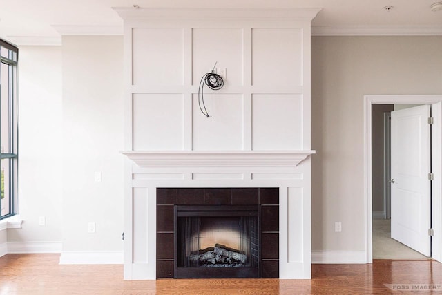 details with a tiled fireplace, wood-type flooring, and ornamental molding