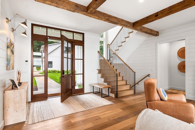 entryway featuring hardwood / wood-style flooring, wooden walls, and beam ceiling