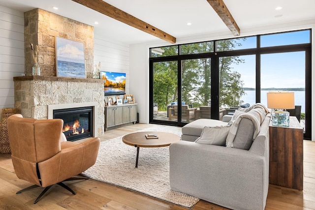 living room featuring wooden walls, light hardwood / wood-style floors, a tile fireplace, and a healthy amount of sunlight