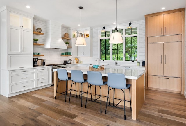 kitchen featuring a breakfast bar, custom range hood, white cabinets, and a kitchen island