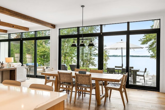 sunroom featuring a water view and beamed ceiling