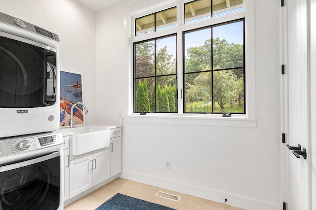 laundry area featuring stacked washer / dryer, light tile patterned flooring, sink, and cabinets