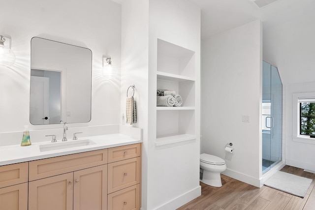 bathroom with built in features, hardwood / wood-style flooring, vanity, an enclosed shower, and toilet