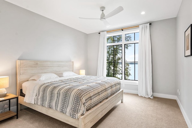 bedroom featuring multiple windows, light carpet, and ceiling fan