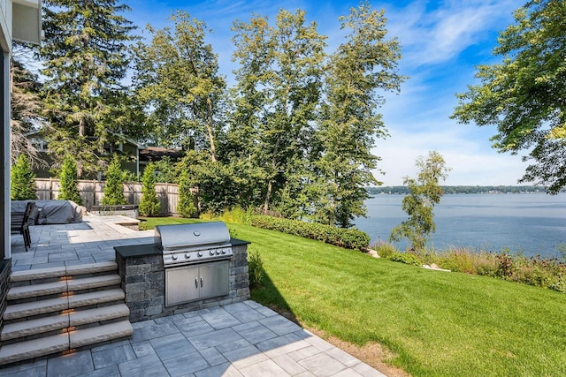 view of patio / terrace with a water view, an outdoor kitchen, and a grill