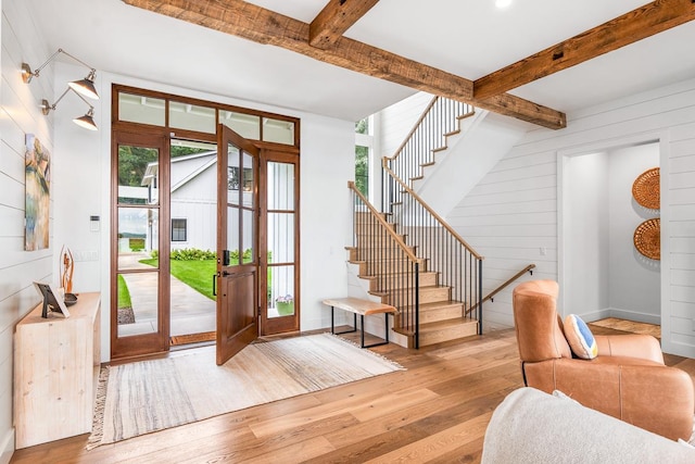 entrance foyer with beam ceiling, wooden walls, and light hardwood / wood-style floors