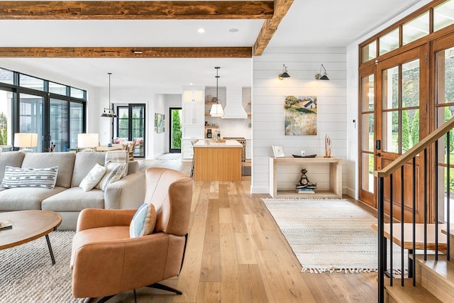 living room featuring beam ceiling, light wood-type flooring, and wood walls