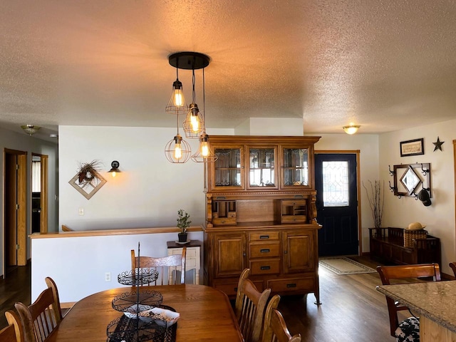 dining room featuring dark wood-type flooring and a textured ceiling