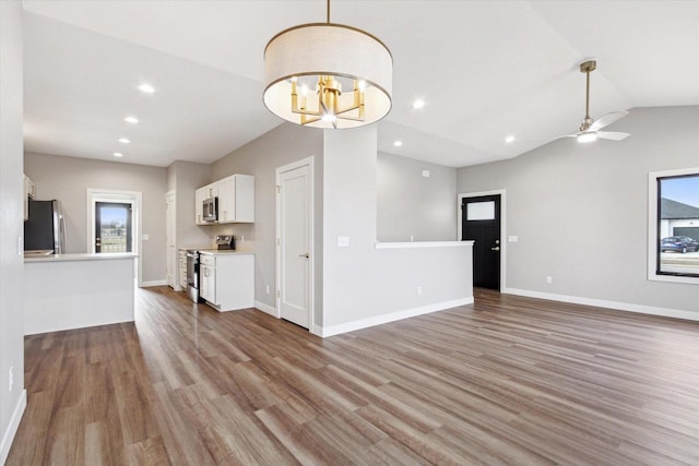 unfurnished living room with lofted ceiling, ceiling fan with notable chandelier, and light wood-type flooring