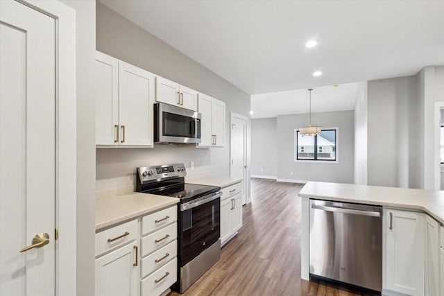 kitchen featuring appliances with stainless steel finishes, dark wood-type flooring, white cabinets, and decorative light fixtures