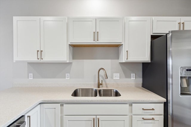 kitchen featuring stainless steel fridge, sink, and white cabinets