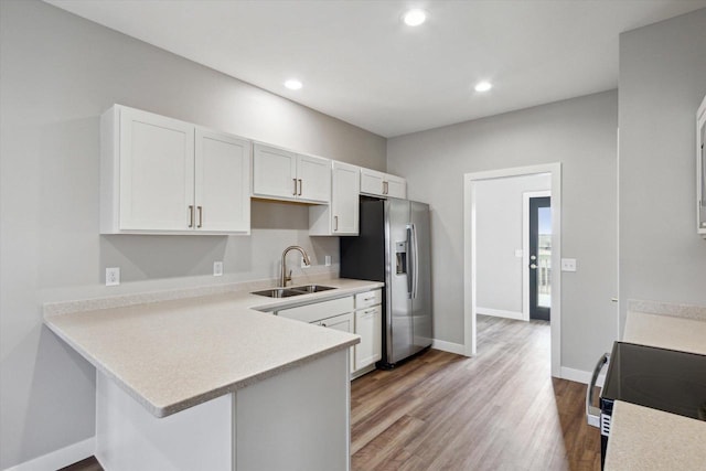 kitchen featuring sink, white cabinetry, stainless steel fridge with ice dispenser, light wood-type flooring, and kitchen peninsula