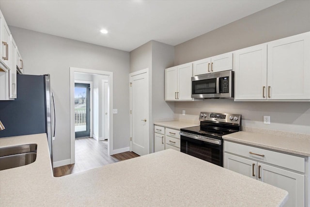 kitchen with sink, light hardwood / wood-style floors, white cabinets, and appliances with stainless steel finishes