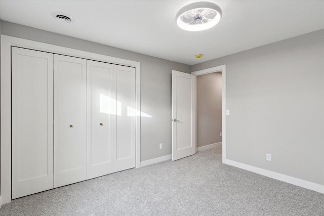 unfurnished bedroom featuring light carpet and a closet