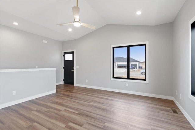 empty room with ceiling fan, vaulted ceiling, and light hardwood / wood-style flooring