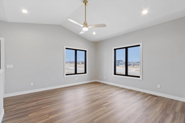 empty room featuring hardwood / wood-style flooring, plenty of natural light, lofted ceiling, and ceiling fan