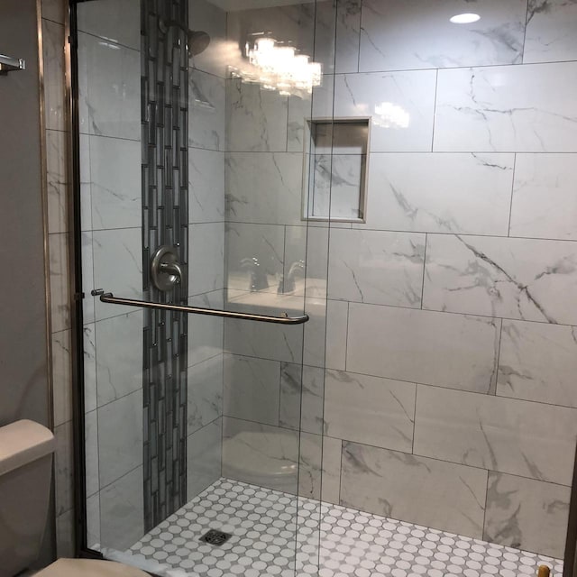 bathroom with a shower with shower door and toilet