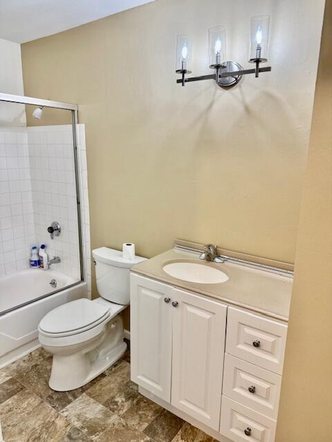 full bathroom featuring vanity, bath / shower combo with glass door, and toilet