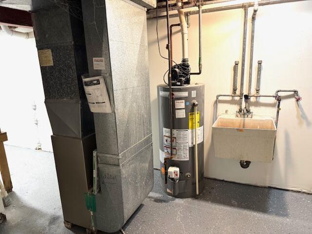 utility room featuring water heater, sink, and heating unit