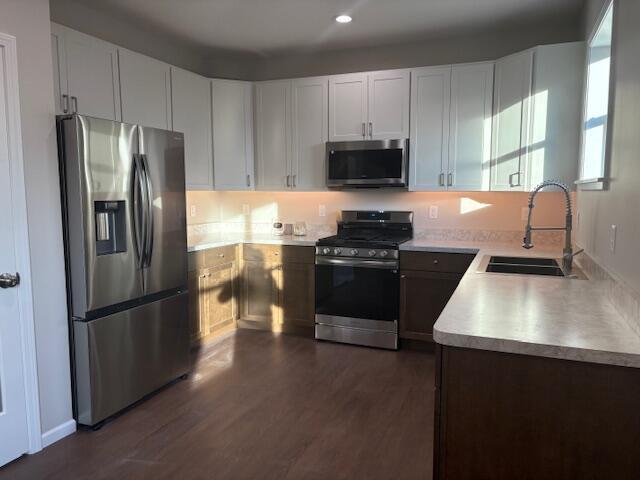 kitchen with dark hardwood / wood-style flooring, sink, stainless steel appliances, and white cabinets