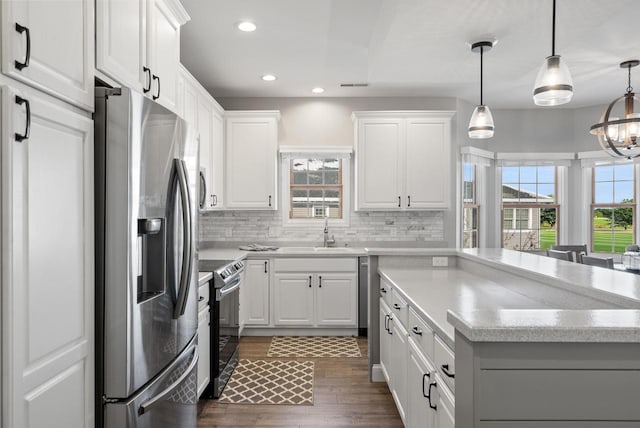 kitchen featuring white cabinetry, hanging light fixtures, sink, and appliances with stainless steel finishes