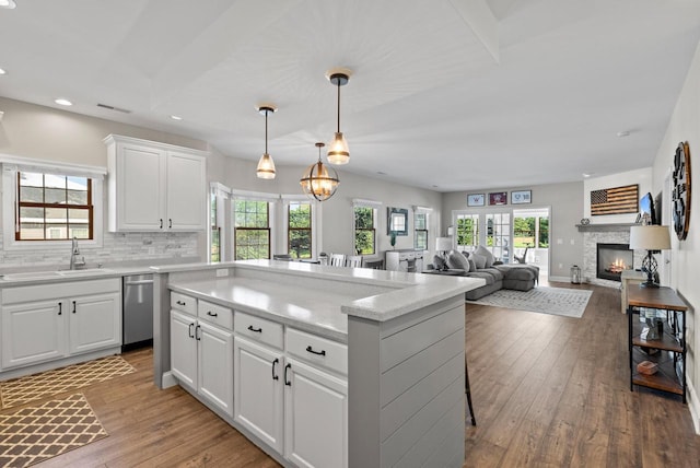 kitchen featuring decorative light fixtures, dishwasher, sink, and white cabinets