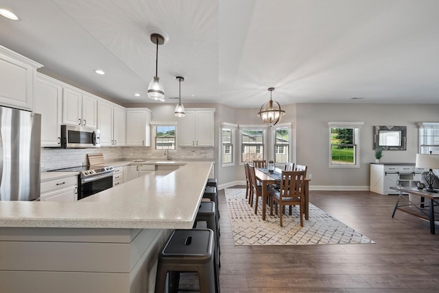 kitchen featuring pendant lighting, white cabinetry, dark hardwood / wood-style flooring, decorative backsplash, and stainless steel appliances